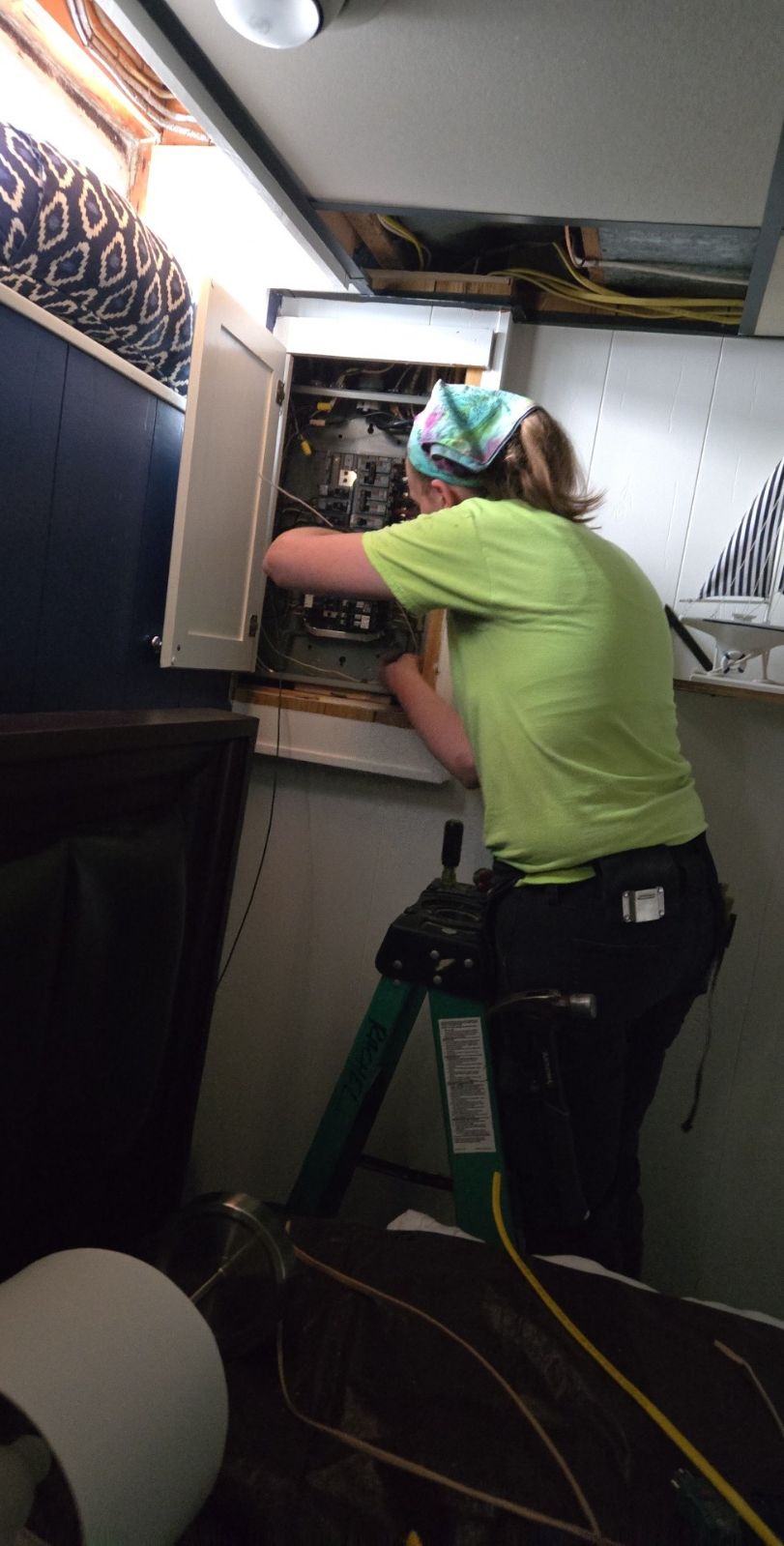 Energize Electric electrician servicing a residential panel tucked inside a cabinet